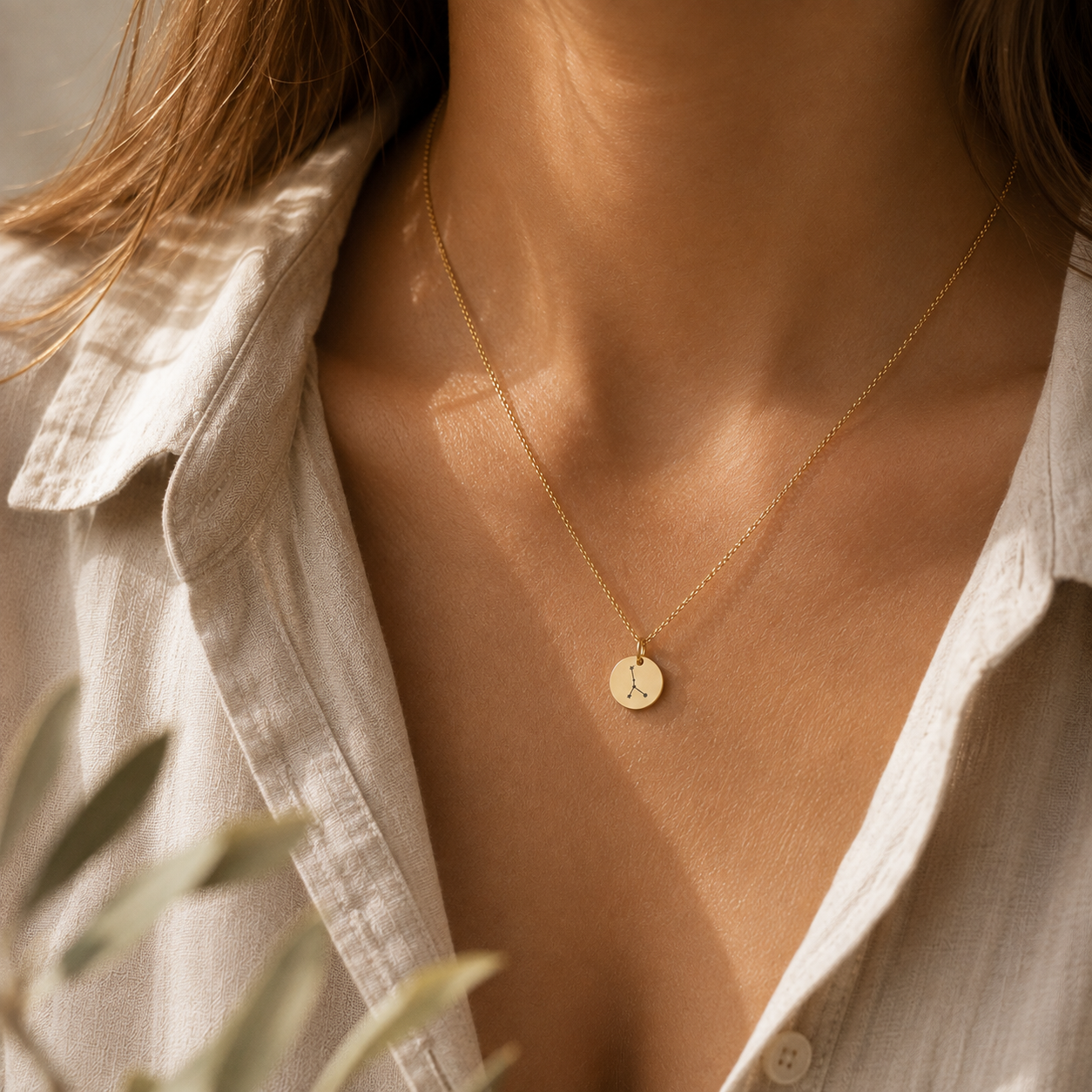 Goldene Sternzeichen-Kette mit rundem graviertem Anhänger und feinem Sternbild, getragen am Hals – personalisierbarer Zodiac Schmuck.