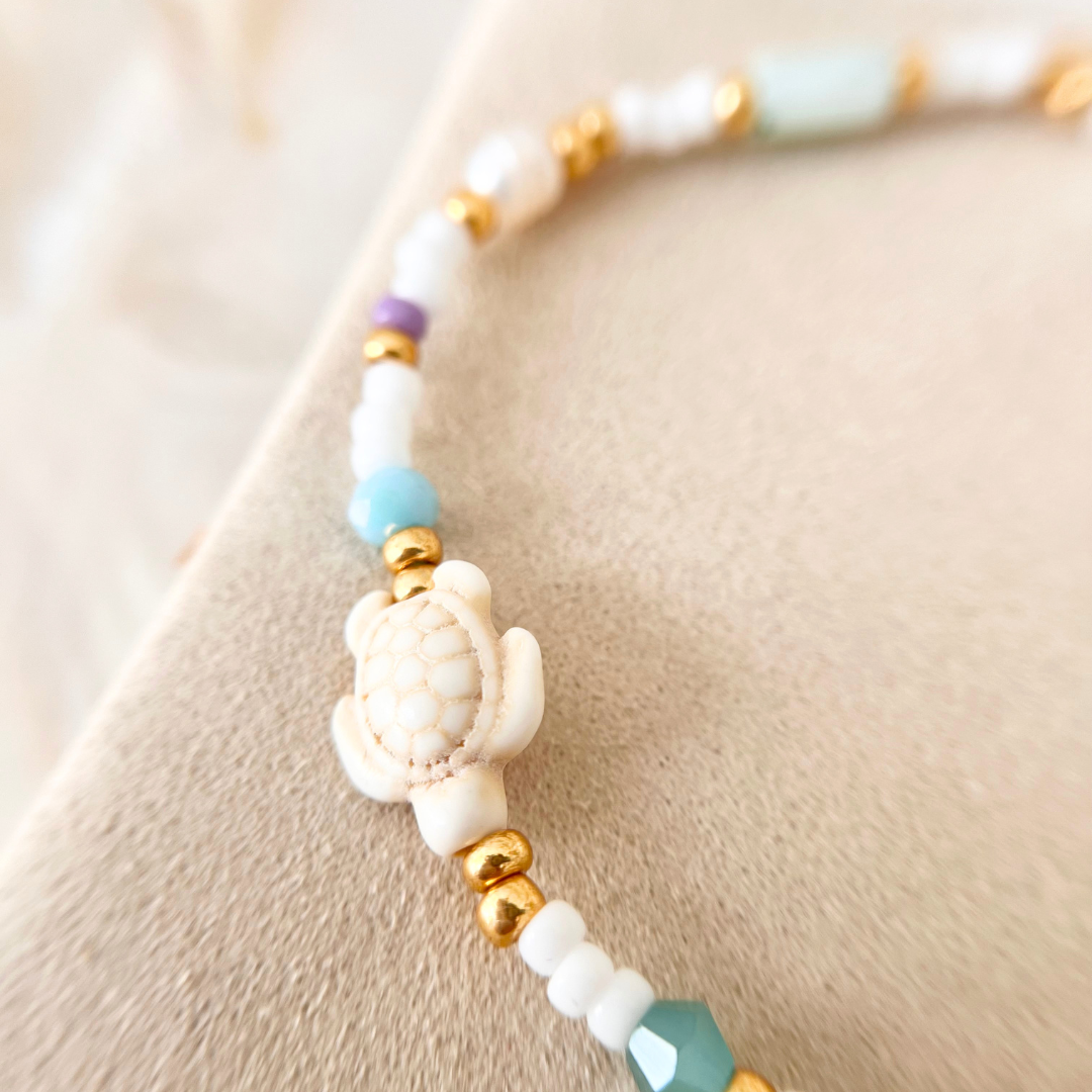 Makroaufnahme vom Schildkröten-Anhänger des Perlenarmbands AMANDA mit goldenen Perlen und türkisfarbener Glasperle – maritimer Schmuck für Frauen