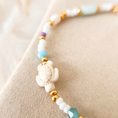 Makroaufnahme vom Schildkröten-Anhänger des Perlenarmbands AMANDA mit goldenen Perlen und türkisfarbener Glasperle – maritimer Schmuck für Frauen