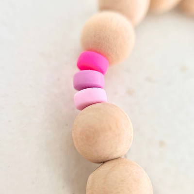 Detailaufnahme der Handykette NALA mit Holzperlen und Acrylperlen in Neonpink und Rosé als praktische Handschlaufe für das Smartphone