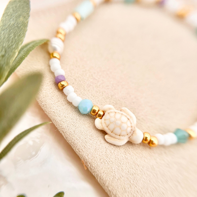 Detailaufnahme vom Perlenarmband mit kleinen weißen Perlen, goldenen Elementen und lila Akzent – filigranes Armband für Frauen im Boho Sommerstil