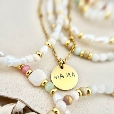 Zarte goldene Kette mit Gravur „MAMA“ in Kombination mit perlmuttfarbenen und pastelligen Perlen – ein liebevolles Schmuckstück als Geschenk für Mütter.