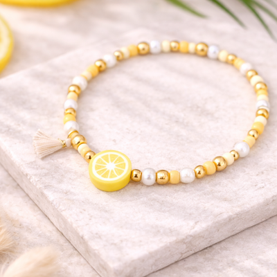 Perlenarmband in Gelb- und Weißtönen mit Zitronen Perle und goldenen Details auf hellem Stein – sommerliches DIY Armband aus Perlenarmband Set