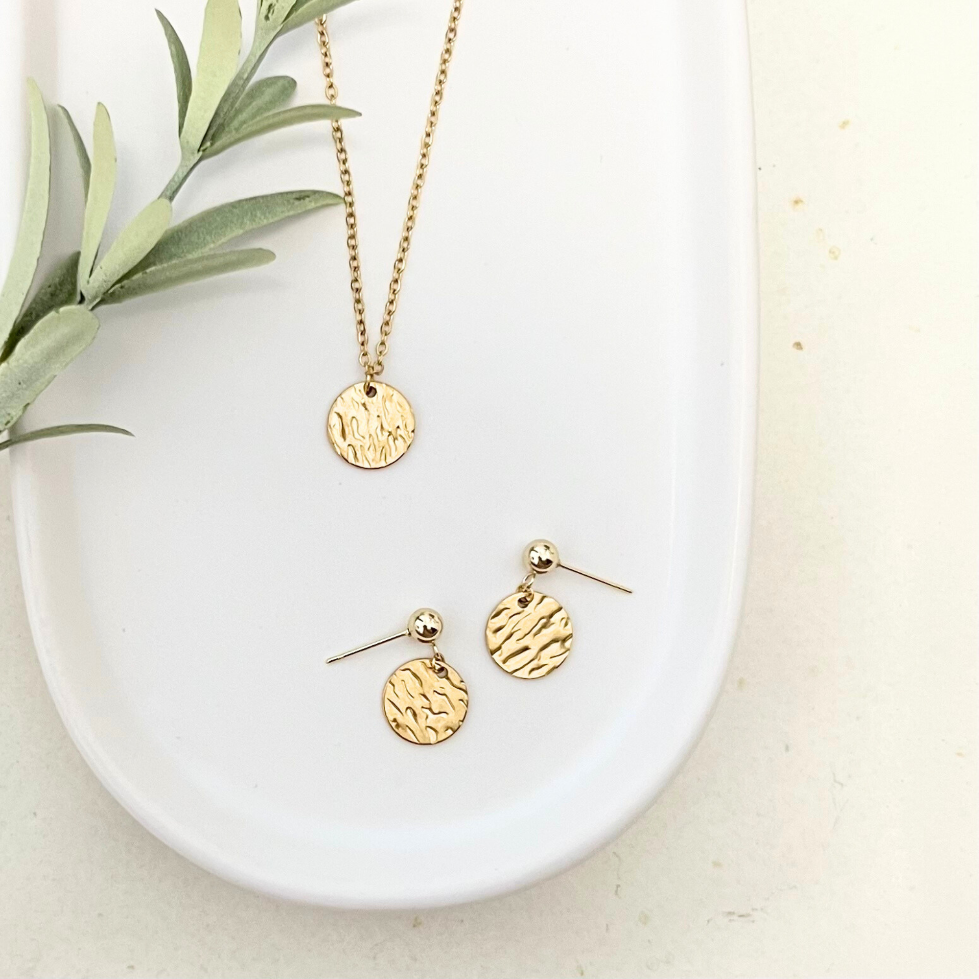 Goldene Edelstahl-Ohrstecker ORO mit passender Kette aus Edelstahl, auf einem Tablet abgebildet, elegant und modern