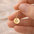 Hand hält eine feine goldene Kette mit rundem Anhänger und Sonnenmotiv, geeignet als persönliches Schmuckstück oder Geschenk mit optionaler Gravur