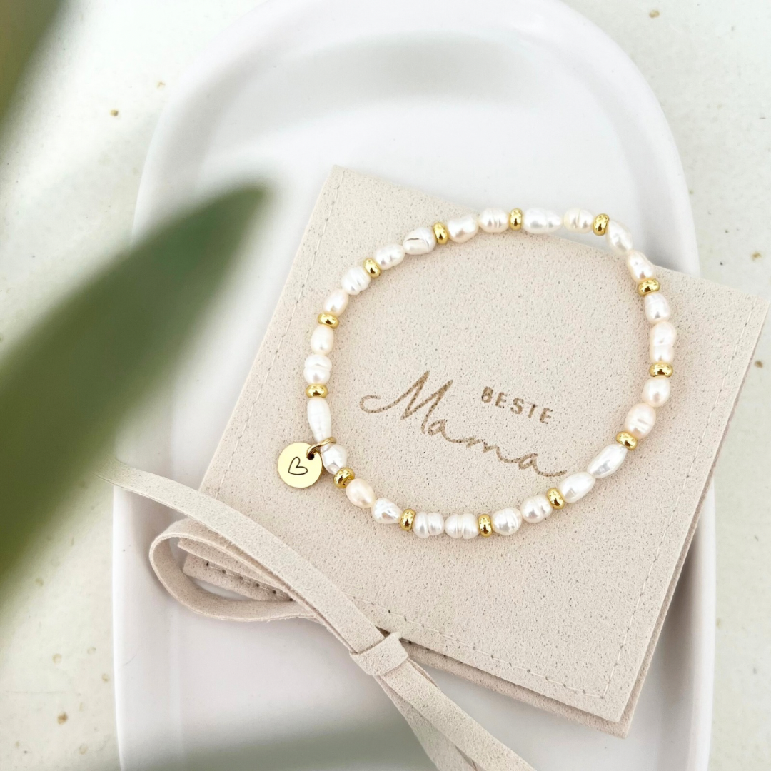 Filigranes Perlenarmband mit Süßwasserperlen und goldenen Elementen, verziert mit einem runden Anhänger mit Herzgravur. Präsentiert auf einer Schmuckverpackung mit der Aufschrift „Beste Mama“ – ideales Geschenk für Muttertag oder besondere Anlässe.