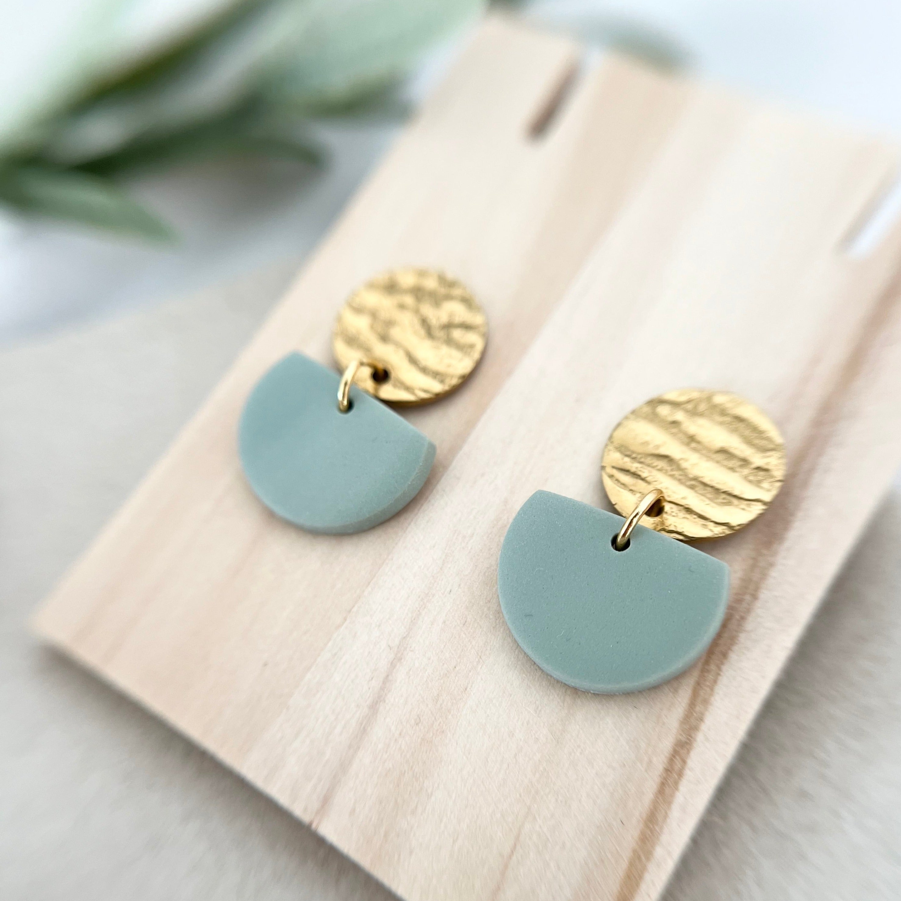 Nahaufnahme der handgemachten Ohrringe ROSEMARY in sanften Grüntönen mit goldfarbenem Edelstahl, die eine elegante und zeitlose Boho-Ästhetik verkörpern