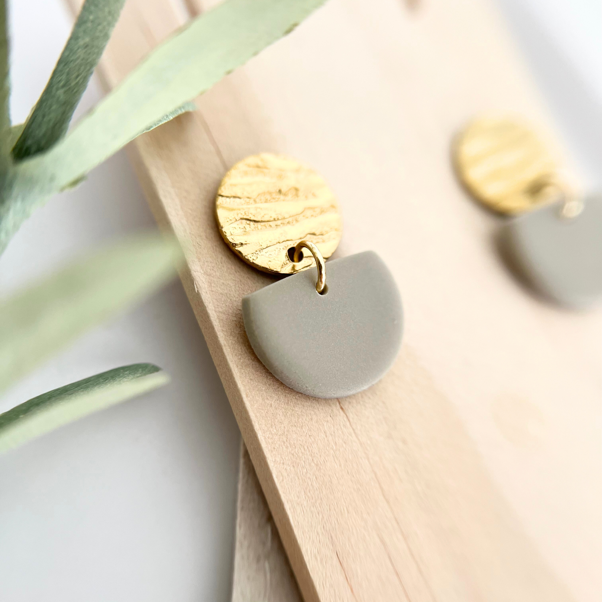 Detailaufnahme eines goldenen Edelstahl-Ohrrings SOL mit gehämmertem Stecker und warmen Tönen in Bronze, Beige und Taupe aus Polymer Clay.
