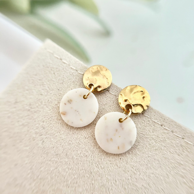 Ein Paar handgemachte Ohrringe mit goldfarbenem Edelstahl-Ohrstecker und feinen floralen Elementen aus Polymer Clay, die die natürliche Schönheit der Trockenblumen und Kräuter betonen.