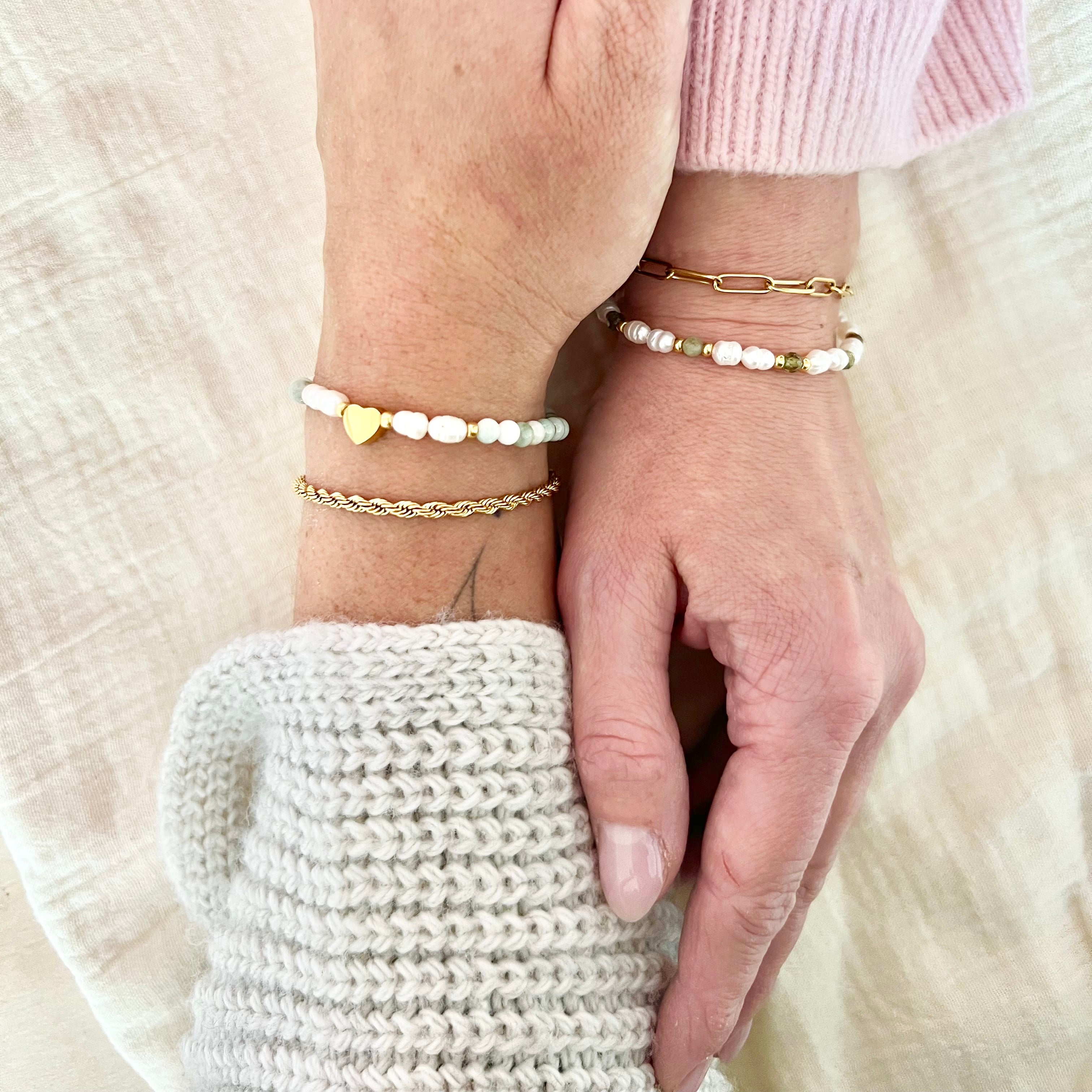 Zwei Freundinnen mit passenden Armbändern in Weiß, Grün und Gold – Symbol für Freundschaft und Nähe, natürliche Lichtstimmung.