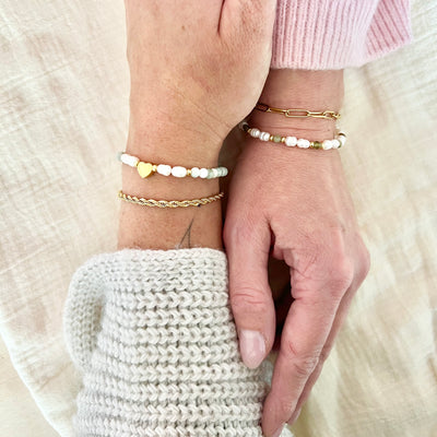 Zwei Freundinnen mit passenden Armbändern in Weiß, Grün und Gold – Symbol für Freundschaft und Nähe, natürliche Lichtstimmung.