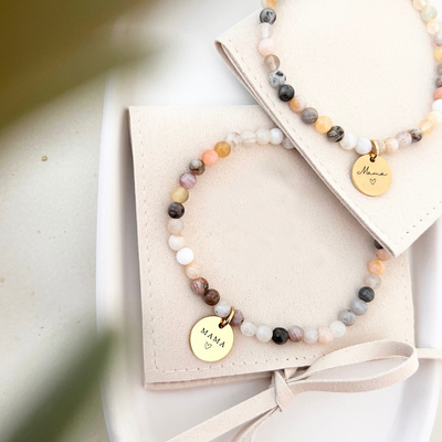 Detailaufnahme von Perlenarmband mit kleinen Perlen in Naturtönen und graviertem Mama Anhänger, hochwertiger Schmuck für Frauen als Geschenk zur Geburt oder zum Muttertag