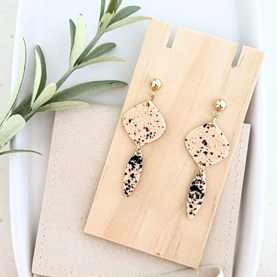 Ein Paar handgemachter Ohrringe MIRAMAR mit Dalmatiner-Optik aus Polymer Clay und Edelstahl, auf Holz drapiert, in Gold oder Silber erhältlich