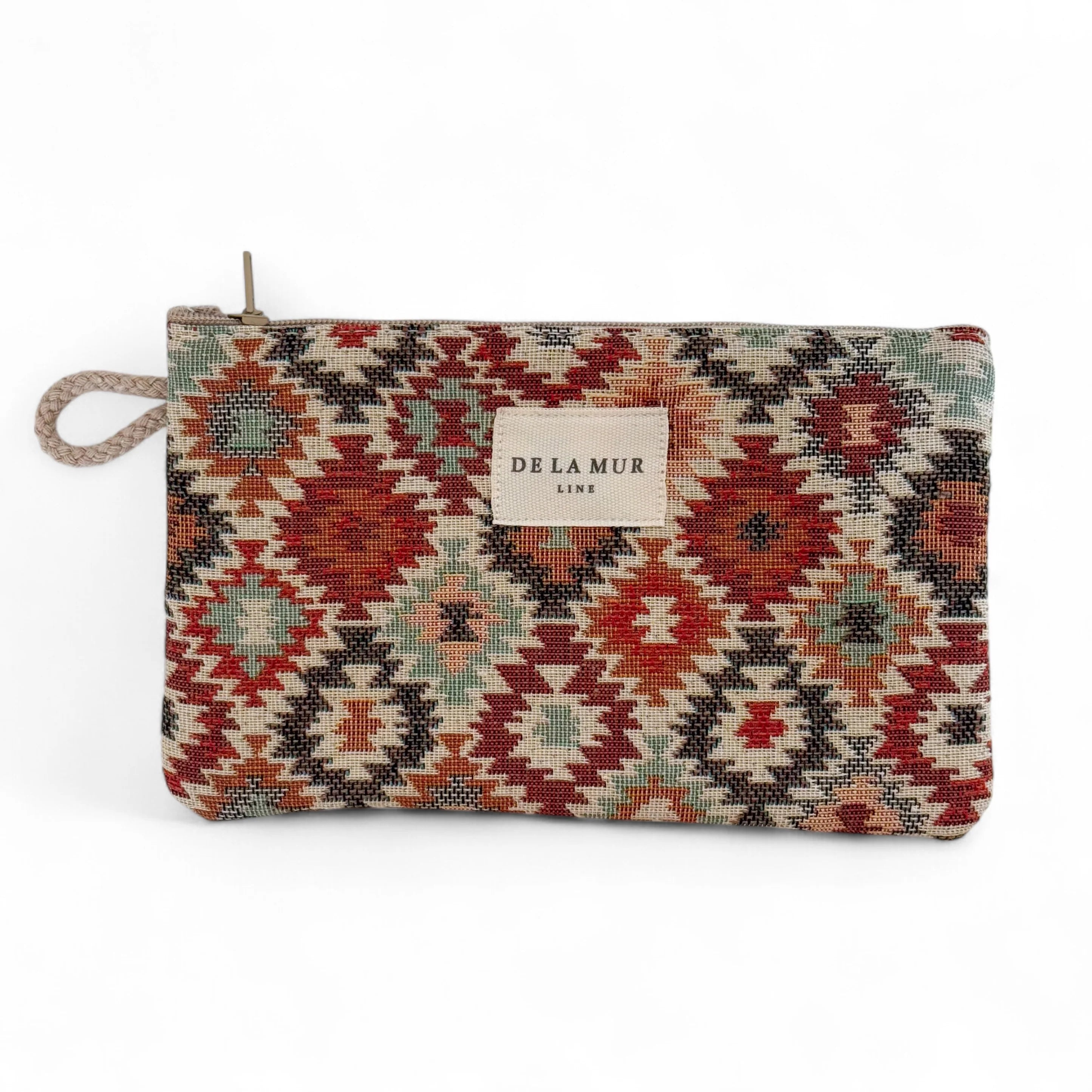Kleines rechteckiges Jacquard-Täschchen von DE LA MUR mit feinem Rautenmuster in Rostbraun, Olivgrün, Beige und Hellblau, Reißverschluss oben und seitlicher Kordelschlaufe. Dient zur Aufbewahrung von Kosmetik, Pflegeartikeln oder Schmuck.