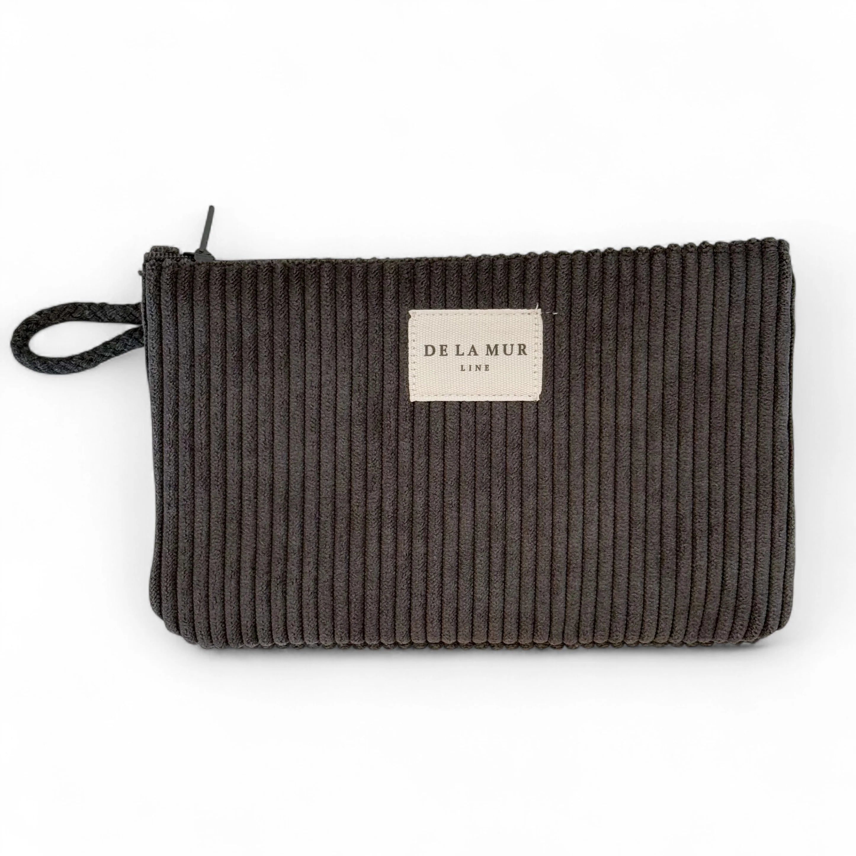 Kleine rechteckige Tasche von DE LA MUR aus anthrazitfarbenem Cordstoff mit Rippenstruktur, Reißverschluss oben und seitlicher Kordelschlaufe. Dient zur Aufbewahrung von Kosmetik, Pflegeartikeln, Schmuck oder als Portemonnaie.