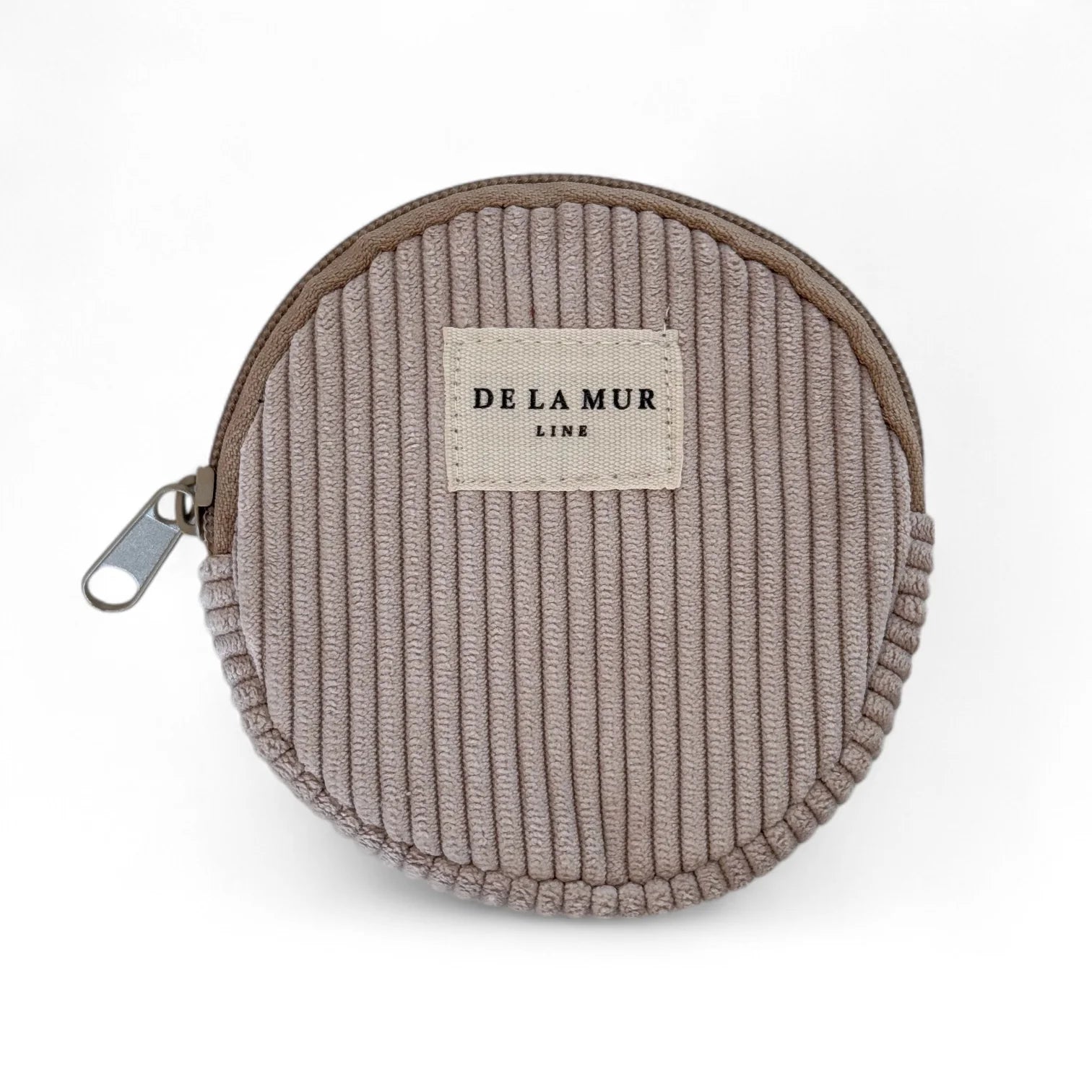 Rundes Portemonnaie aus beigem Cordstoff von DE LA MUR mit Reißverschluss und Stofflabel. Handgefertigt in Barcelona – stilvolles Accessoire für Karten und Münzen.