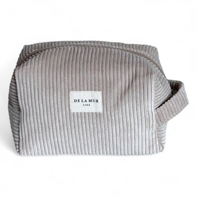 Abgebildet ist eine beige-braune Beauty Bag aus Cordstoff mit Rippenstruktur von DE LA MUR. Die Tasche hat einen seitlichen Griff und eignet sich zur Aufbewahrung von Kosmetik, Pflegeartikeln oder Schmuck – ideal für Reisen oder den Alltag.