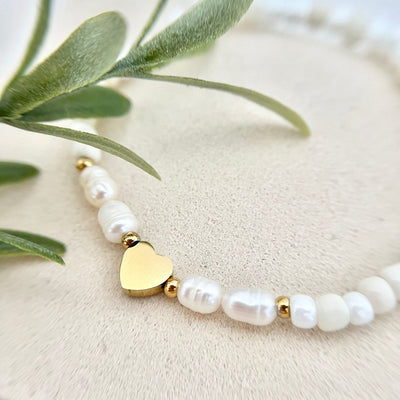 Nahaufnahme des goldfarbenen Herzanhängers auf dem Cremeweiß Süßwasserperlen-Armband